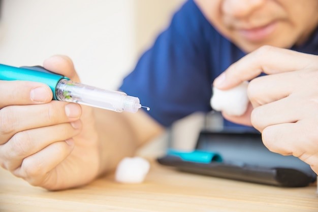 Man drawing insulin into a syringe from a vial, preparing for injection.