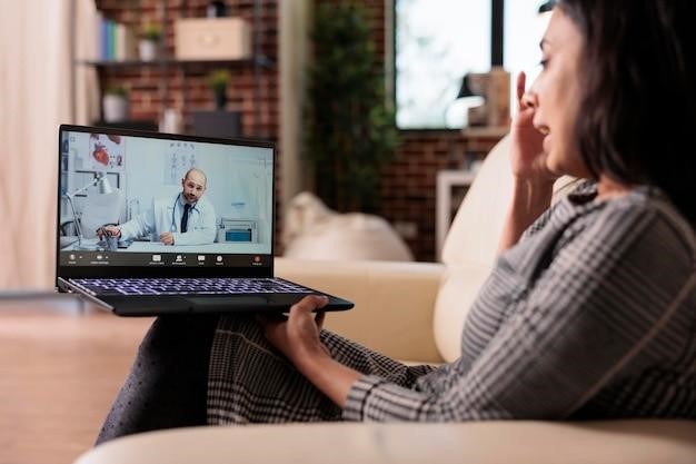 Woman having an online video consultation with a doctor on her laptop from home.
