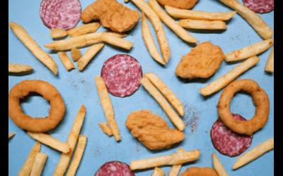 Fried foods, french fries, chicken nuggets, and salami scattered on a blue surface.
